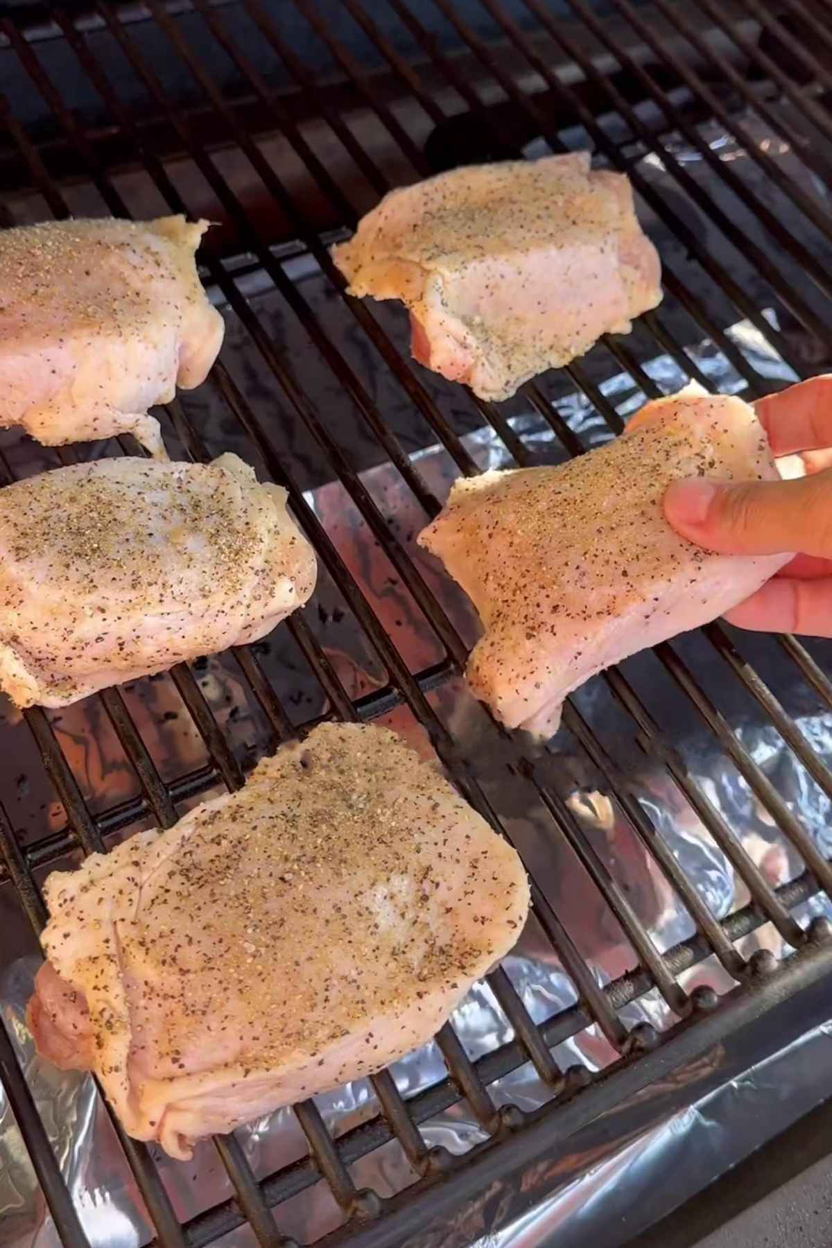 raw seasoned chicken thighs on a grill